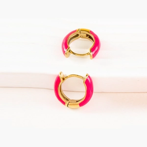 Nahaufnahme der goldenen U-förmigen Huggie-Ohrringe mit leuchtend pinker Emaille