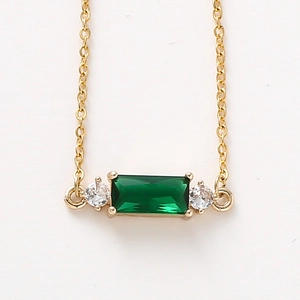 Detailed close-up of emerald green square crystal pendant with gold chain