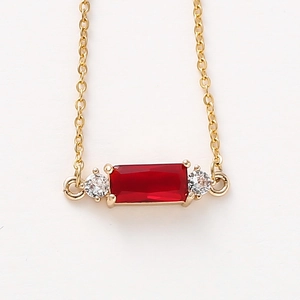 Macro view of a gold chain necklace with a rectangular red ruby and zircon accents