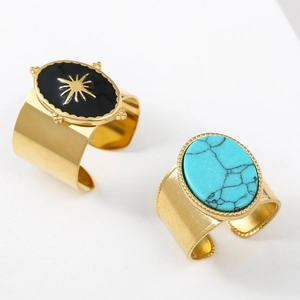 Close-up of gold-plated rings with black enamel star and turquoise stone in vintage style