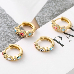 Vue détaillée de boucles d'oreilles œil porte-bonheur dorées avec micro-pavage de zircons