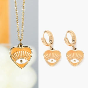 Détail de parure bijoux cœur mauvais œil en or avec émail orange et rayons solaires
