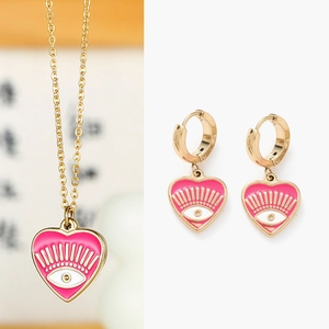 Détail du pendentif cœur en émail rose œil de protection et boucles d'oreilles dorées
