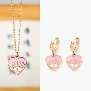 Détails de l'ensemble collier et boucles d'oreilles cœur en émail rose avec motif œil