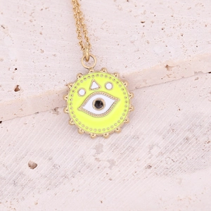 Close-up of golden evil eye pendant with yellow enamel on a textured stone base