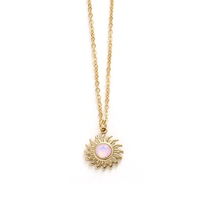 Detail of sun pendant necklace with pink stone center on a delicate gold chain