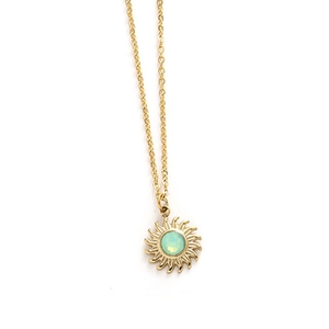 Close-up of golden sun pendant with mint green gemstone on a thin cross chain