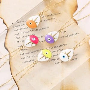Colorful water drop evil eye pendants on gold chains over vintage parchment paper