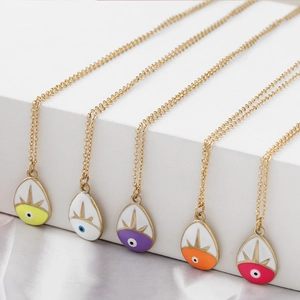 Detail view of five colorful enamel evil eye teardrop pendants on gold necklaces