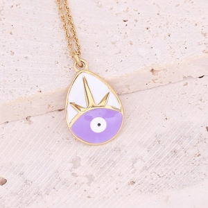 Macro shot of gold waterdrop enamel pendant with evil eye motif on stone surface