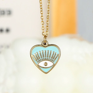 Macro detail of gold-plated heart pendant featuring an evil eye enamel design
