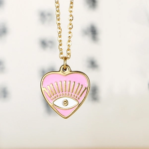 Macro shot of 14k gold plated heart pendant with pink enamel and evil eye motif