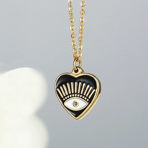 Close-up of a heart-shaped evil eye pendant with black enamel and 14k gold-plated finish
