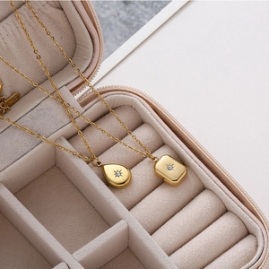 Macro detail of gold-plated pendant necklaces with starburst set zircons in velvet box