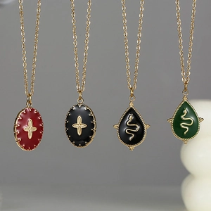 Detailed view of vintage cross and snake pendants in red, black, and green enamel finishes