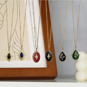 Detail of vintage 14K gold cross and snake pendants with enamel and gemstones
