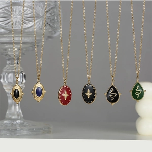 Detailed close-up of retro snake and cross enamel pendants on gold stainless steel necklaces