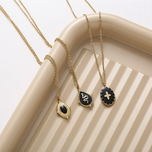 Detailed view of three 14K gold-plated necklaces with black enamel cross and star pendants