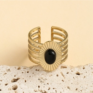 Detail of vintage gold ring with oval black stone on white porous stone pedestal