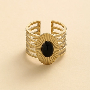 Detailed close-up of retro hollow golden ring with oval black stone and sunburst relief