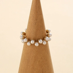 Bague élégante en acier inoxydable doré ornée de perles blanches sur support en bois