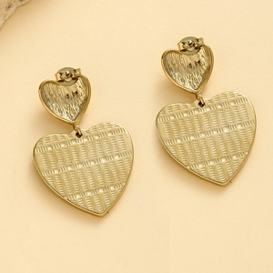 Detail of gold heart earrings with intricate textured mesh pattern and double drop design