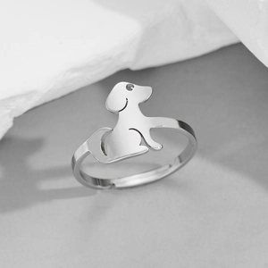 Close-up of a silver minimalist puppy shaped open adjustable ring on a stone texture