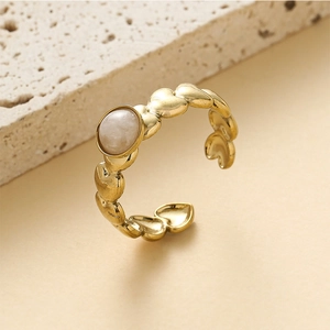 Close-up of golden heart-shaped band ring with a round opal-like stone inlay