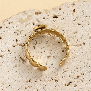 Macro shot of gold stainless steel heart ring with white gemstone on natural rock