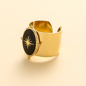 Detail view of gold adjustable wide cuff ring with black sunburst oval medallion