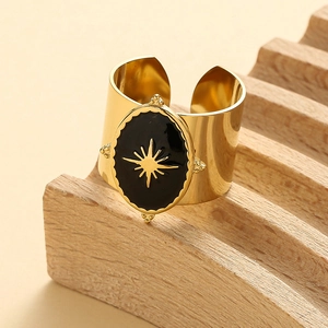 Detail of wide black enamel ring with golden starburst on a wooden stand