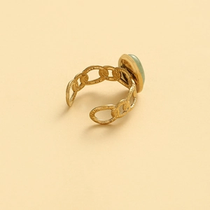 Vintage gold chain link ring with a translucent green oval stone on a beige background