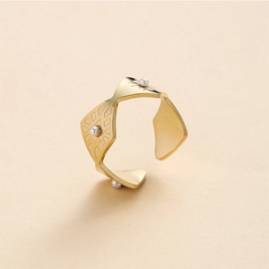 Détail macro d'une bague ajustable dorée avec perles blanches et gravures géométriques