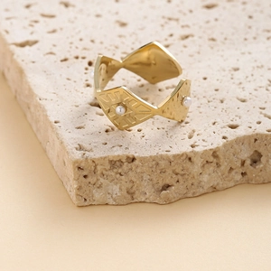 Détail macro d'une bague géométrique dorée avec perles sur socle en pierre naturelle