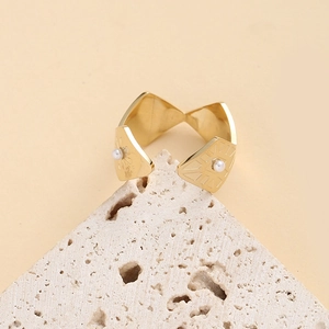 Bague ouverte géométrique dorée avec motifs radiaux et perles blanches sur pierre