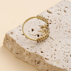 Detail of gold leaf ring with zircon stones on a natural textured stone background