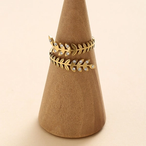 Golden stainless steel adjustable leaf ring with zircon stones on a wood stand