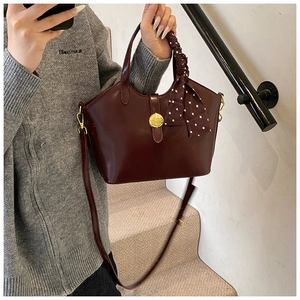 Détail d'un sac en cuir bordeaux avec boucle dorée et foulard en soie à pois élégant