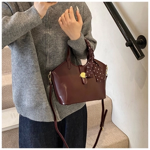 Détail du sac seau bordeaux avec boucle dorée et foulard à pois sur la poignée