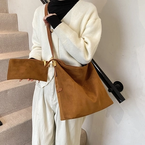 Grand sac cabas en daim marron avec pochette assortie, porté par un mannequin en escalier
