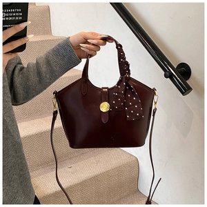 Détail du sac à main bordeaux avec boucle en métal doré et foulard en soie sur la poignée