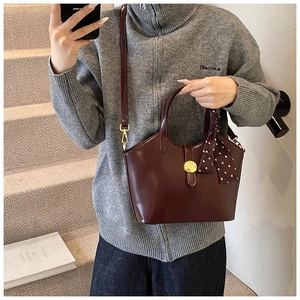 Détail d'un sac rétro bordeaux en cuir PU avec foulard à pois et boucles dorées
