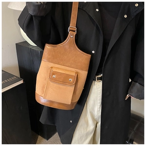 Detail view of two-tone brown suede bucket bag with front pocket and metal buckle