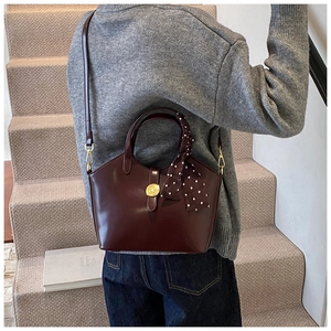 Sac seau bordeaux avec boucle dorée et foulard à pois porté à l'épaule