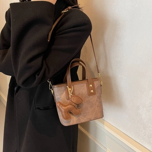 Retro brown bucket bag with cute dog charm shown on a black wool coat for women