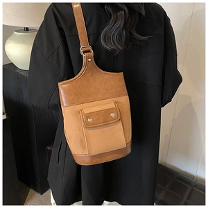 Detail view of brown patchwork crossbody bag with suede texture and metal snaps