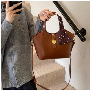 Détail du sac fourre-tout marron vintage avec boucle dorée et foulard en soie au poignet