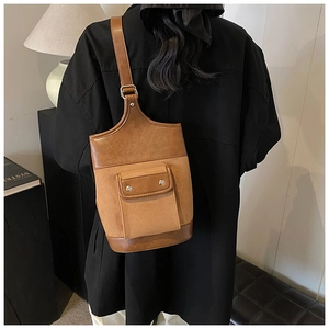 Detail of retro brown suede and leather bucket bag showing dual textures and metal buckle
