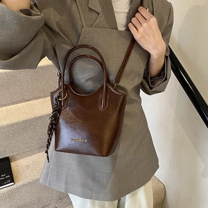 Bolso cubo vintage marrón de piel sintética con asas y cinta decorativa para otoño 2024