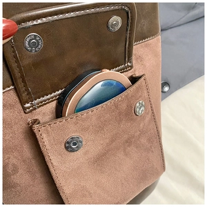 Macro detail of faux suede shoulder bag featuring dual silver magnetic snap fasteners